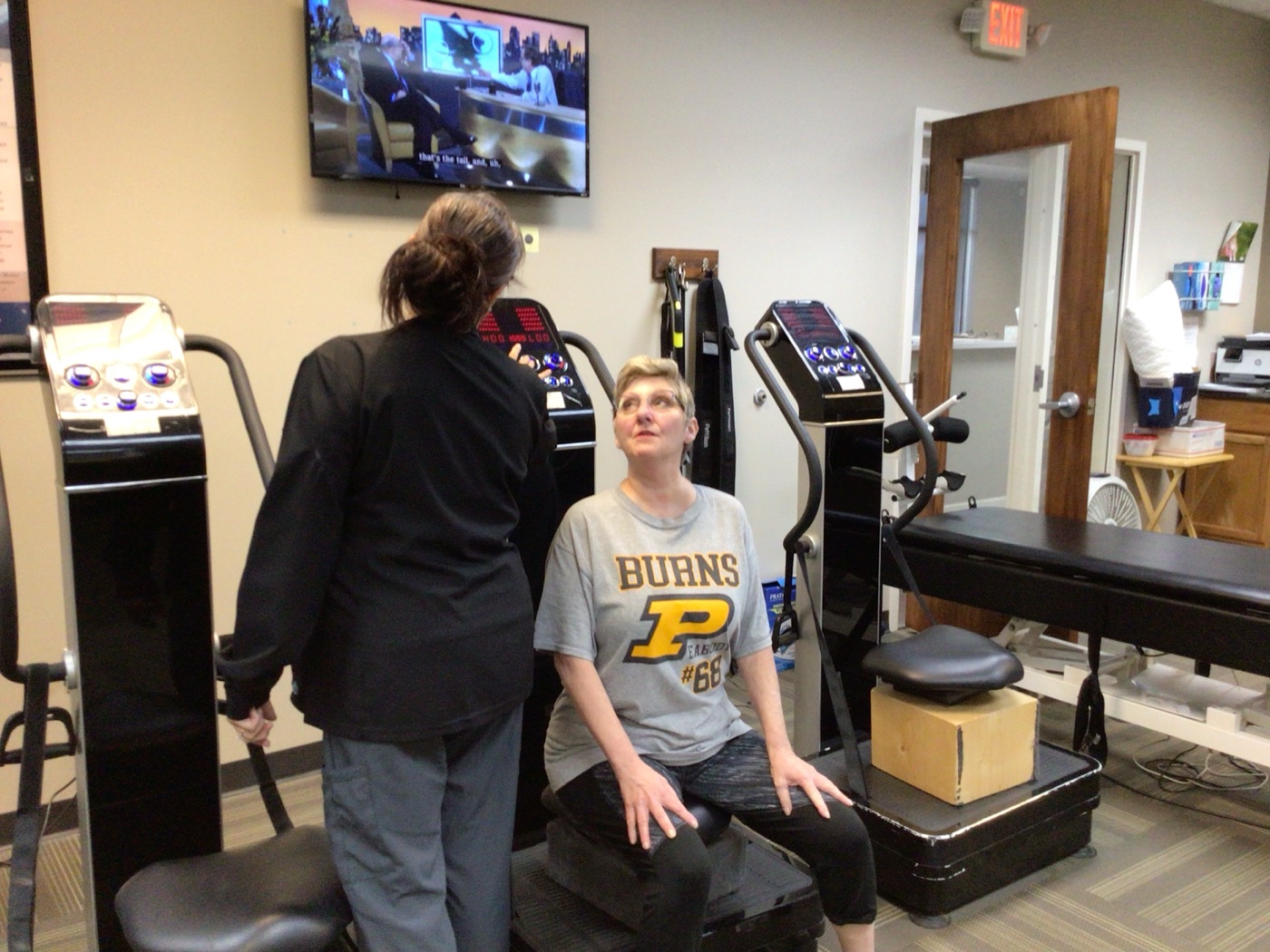 A patient using a whole-body vibration plate during rehab